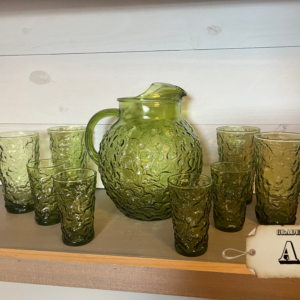 Hero Image: Vintage Anchor Hocking Milano avocado green pitcher with eight matching tumblers Angle View: 1960s Milano textured glass pitcher and tumbler set Detail Close-Up: Close-up of Milano textured glass pattern in avocado green Maker’s Mark: Anchor Hocking mark on base of pitcher Interior View: Interior of vintage avocado glass pitcher